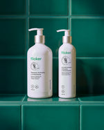 Botellas de shampoo y acondicionador Filoker Anticaída y Antioxidante con dispensador tipo bomba exhibidas en un ambiente de baño sobre azulejos verdes